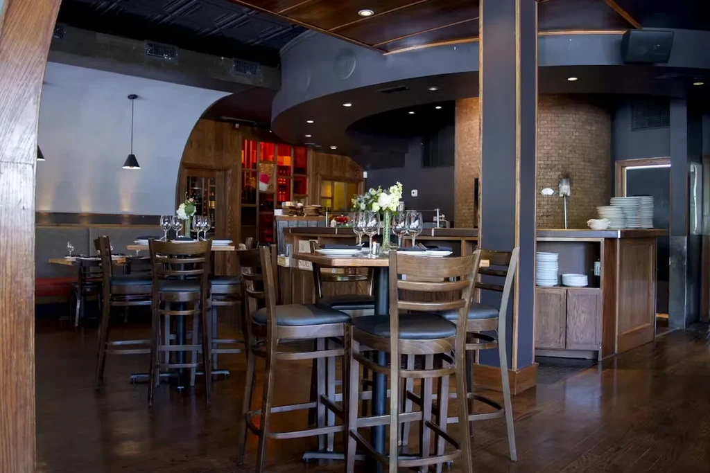 Interior of an elegant, modern restaurant with high-top tables and booths.