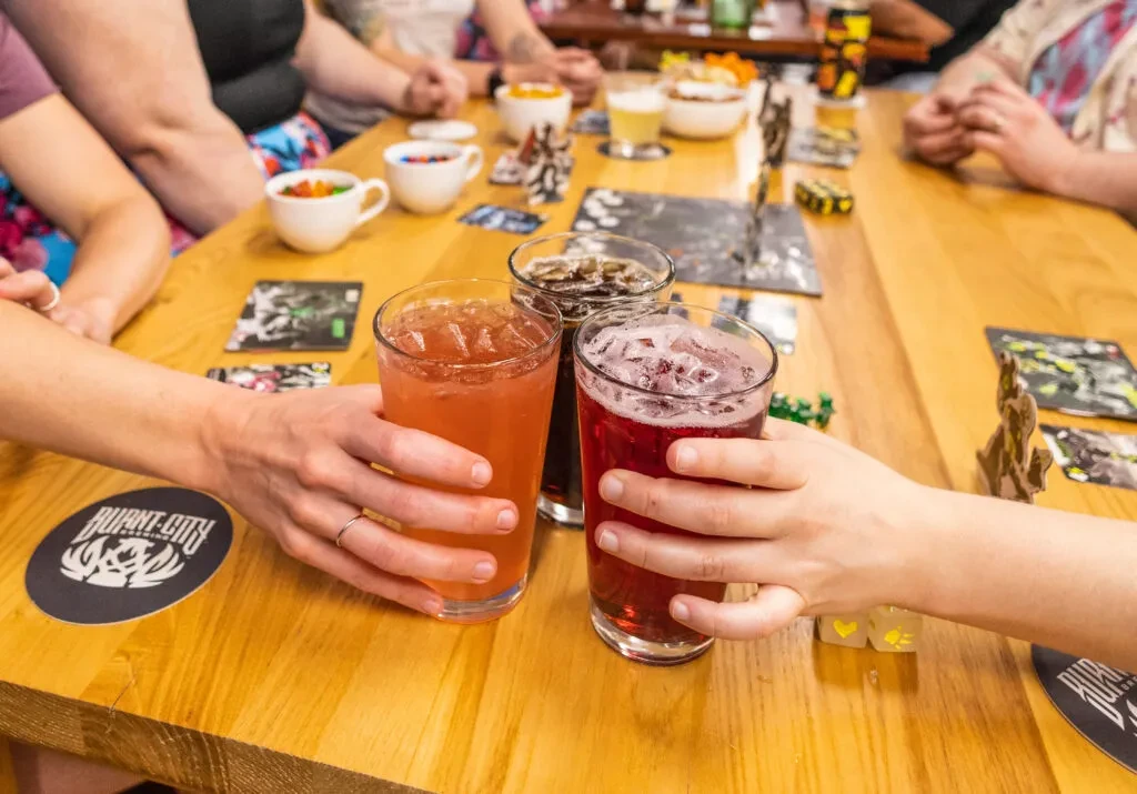 Three iced beverages raised in a toast around a game table.
