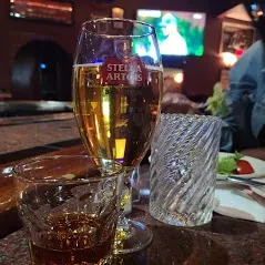 Stella Artois beer, shot glass, and decorative glass at a dim bar.