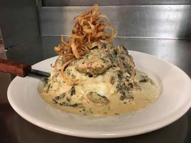 Close-up of creamy mushroom and greens dish with crispy fried onions.