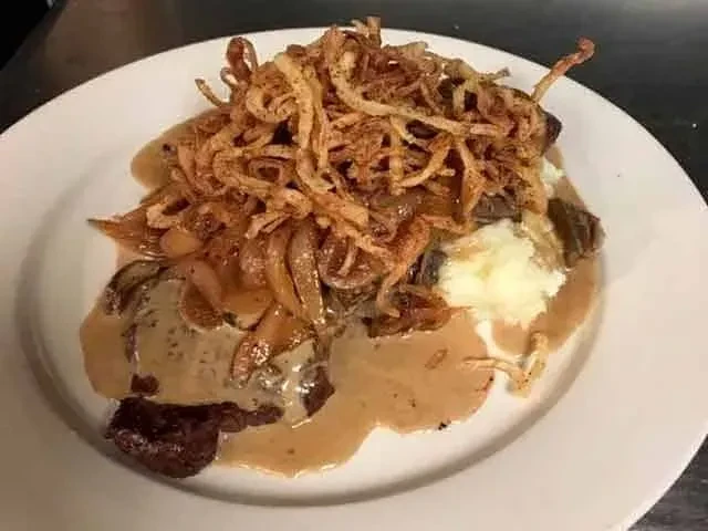 Hearty beef pot roast with mashed potatoes and crispy onions.