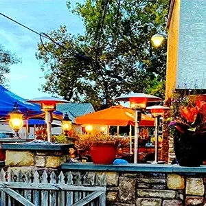 Outdoor patio at dusk with glowing orange patio heaters and umbrella.