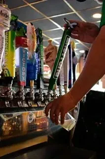 Bartender's hands pour Bud Light from a tap into a glass.