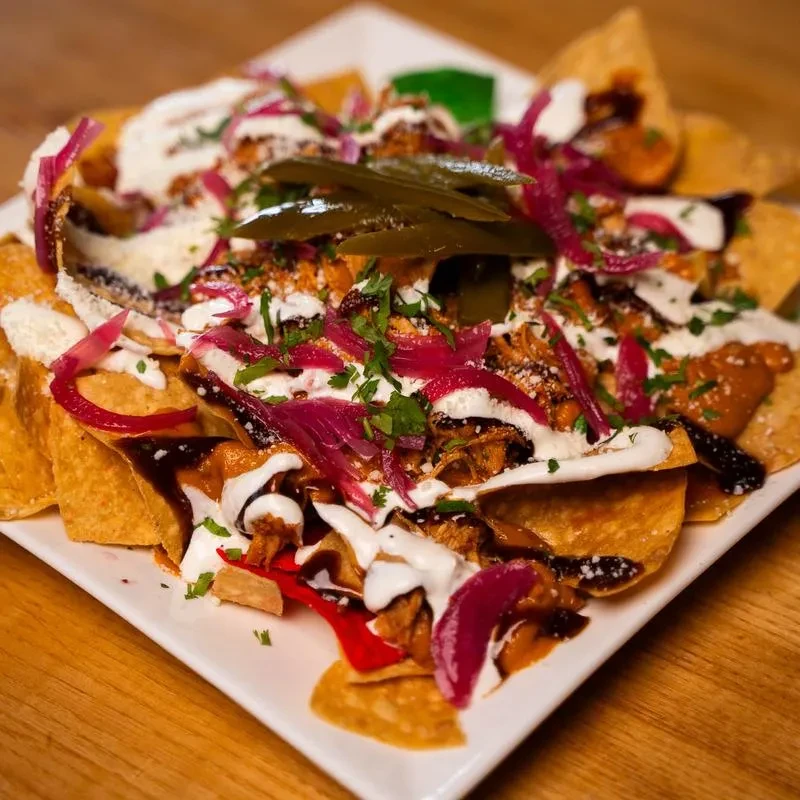 Loaded nachos topped with meat, cheese, sauces, red onions, and jalapeños.