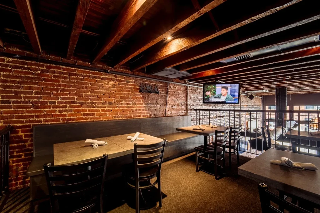 Restaurant interior: exposed brick, wood beams, banquette seating, and a TV.