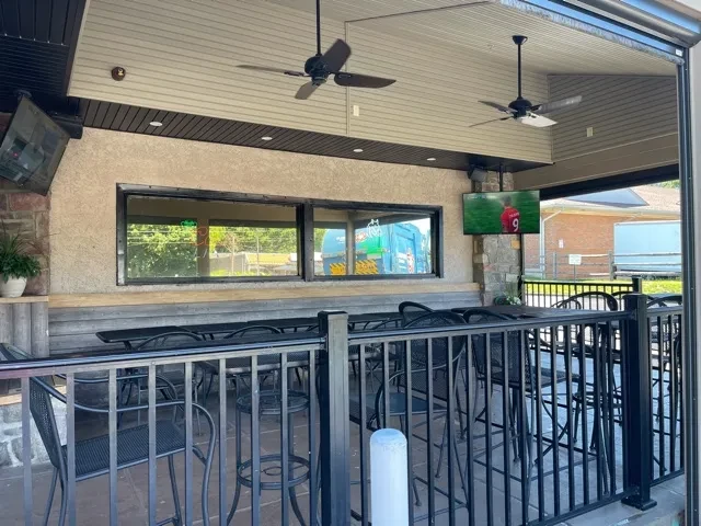 Restaurant patio with black high-top tables and TVs showing soccer.