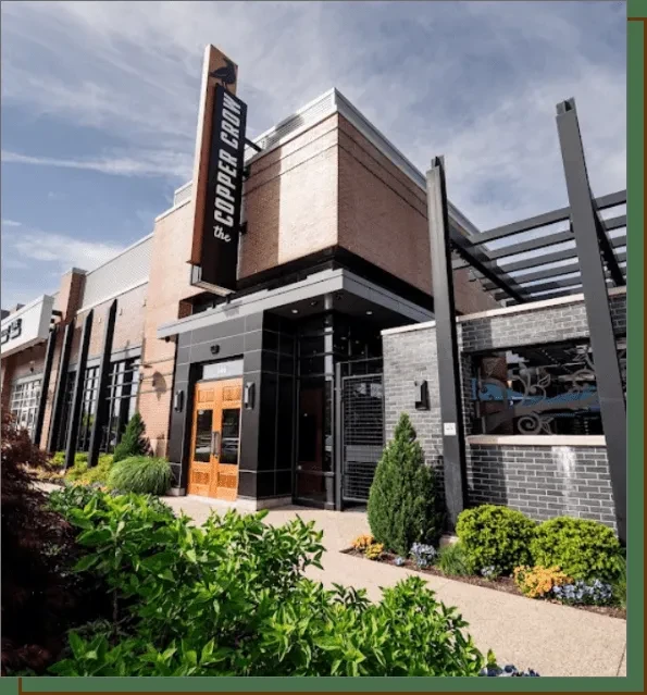 The Copper Crow modern restaurant exterior, brick, dark panels, landscaping.