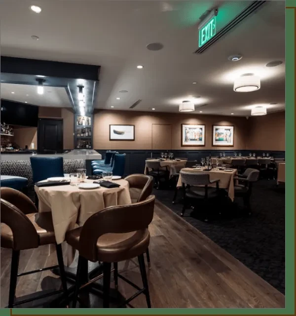 Empty upscale restaurant and bar interior with tables and a well-stocked bar.