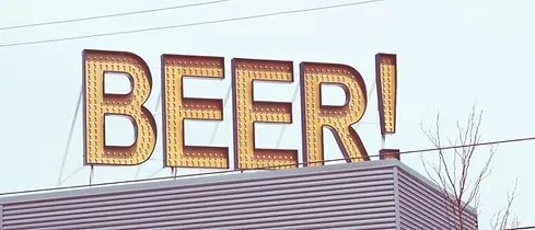 Illuminated marquee 'BEER!' sign on a gray building.