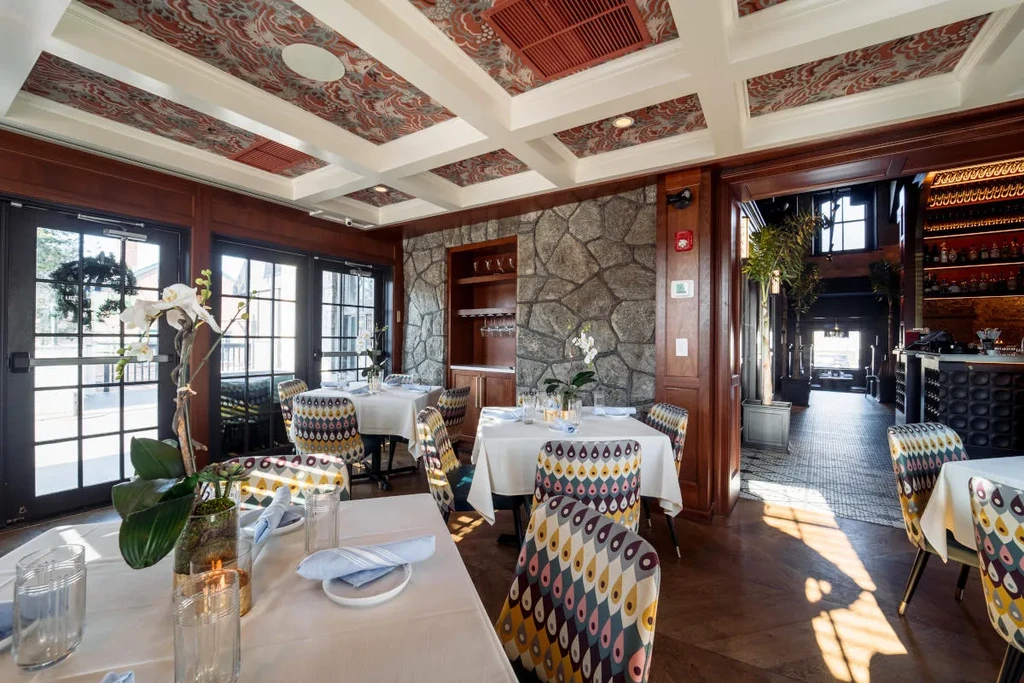 Restaurant interior with orchid centerpiece, peacock chairs, wood, and stone walls.