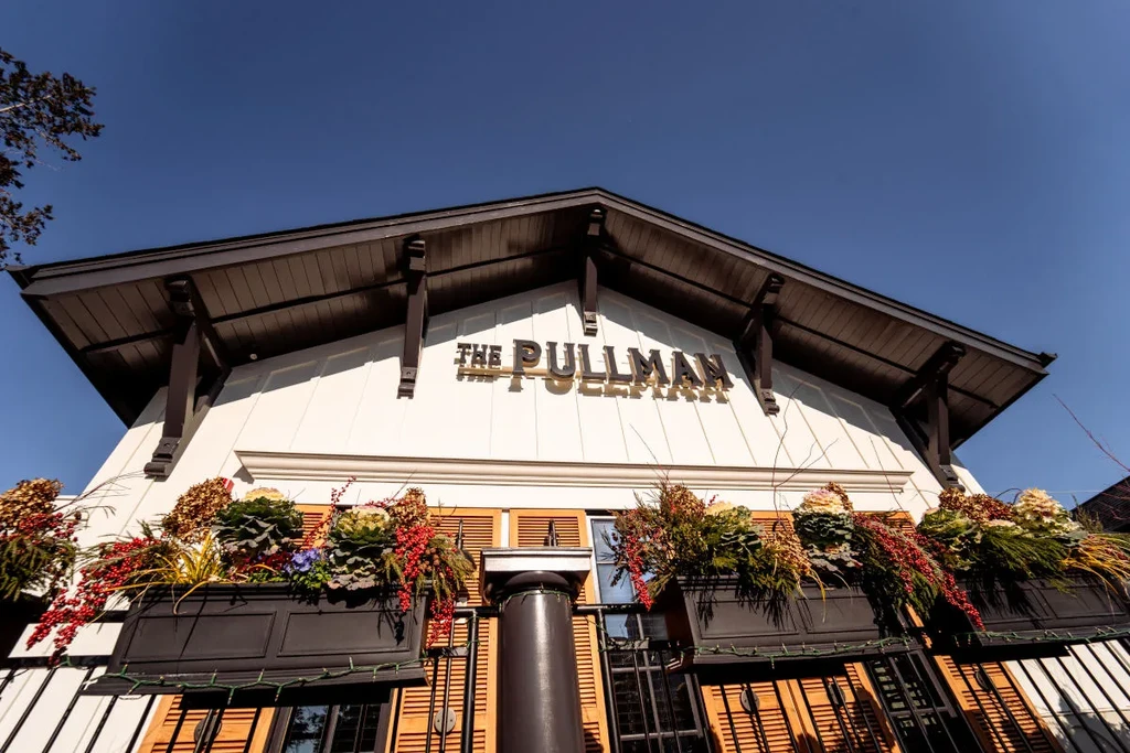 THE PULLMAN restaurant exterior, gold letters, autumn window boxes, blue sky.
