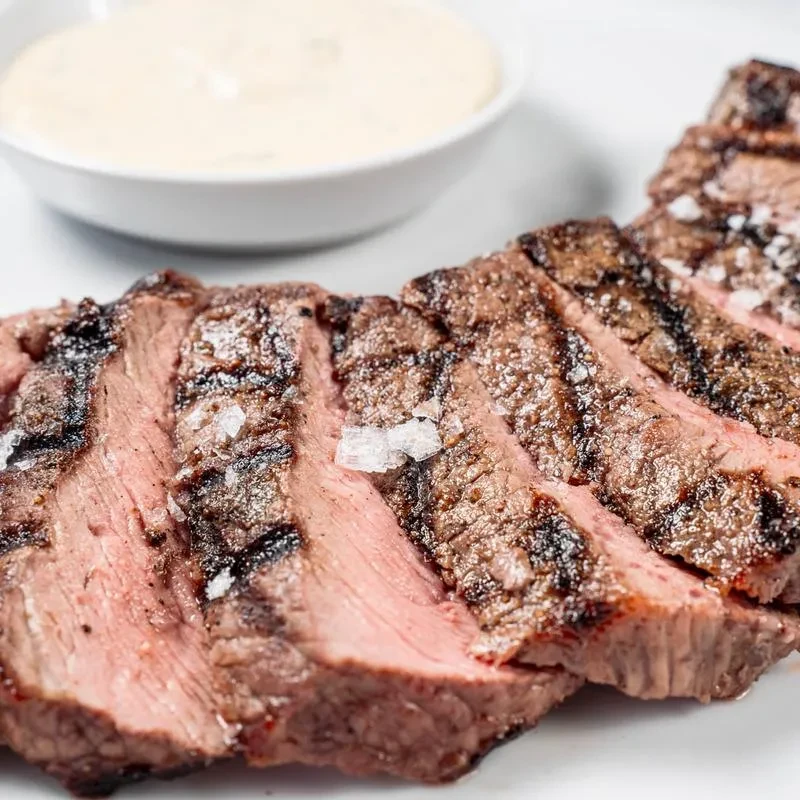 Medium-rare grilled steak slices with prominent grill marks and sea salt.