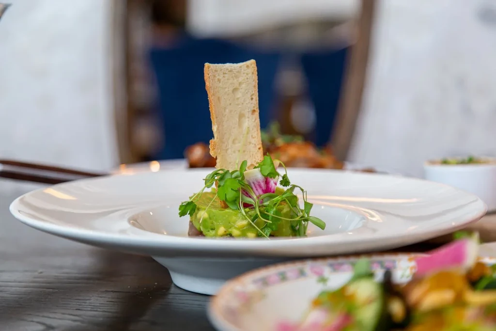 Vibrant avocado tartare with radish, microgreens, and toast.