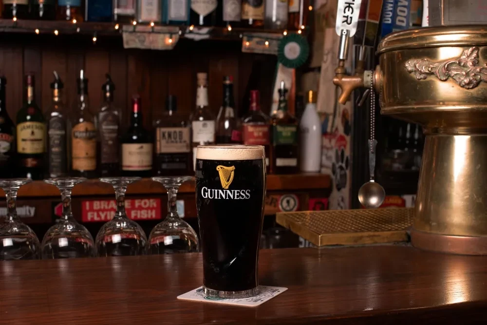 Close-up of a Guinness pint with creamy head on a bar.