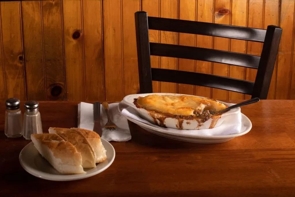 Golden, flaky pot pie, bread, and shakers on a wooden table.