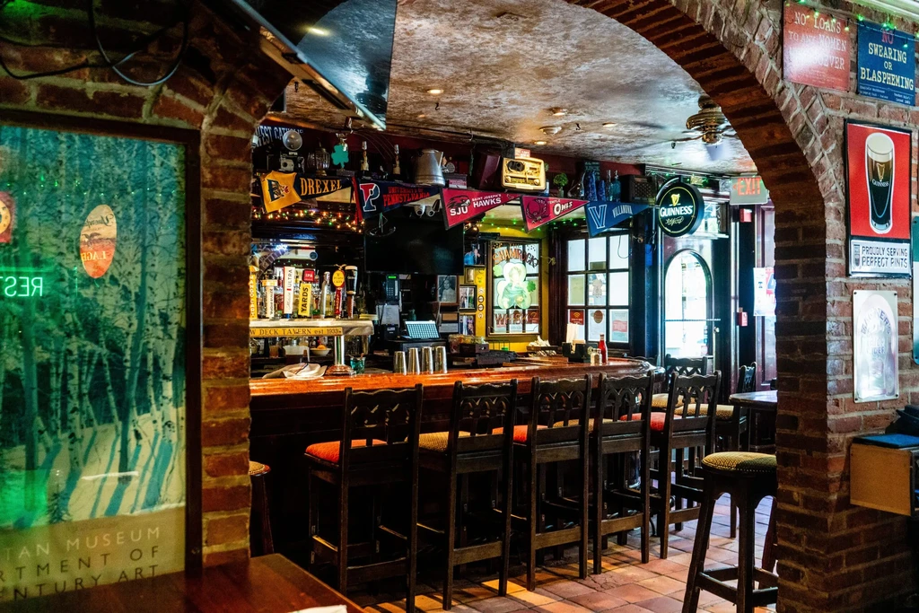 Traditional bar with wood counter, beer taps, and college pennants.