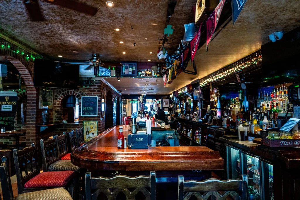 Cozy pub interior with a gleaming wooden bar and extensive liquor display.