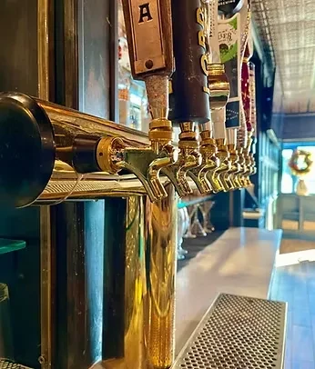Golden beer taps with distinct handles on a bar, no people.