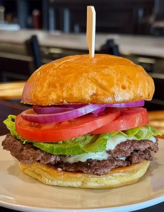 Double-patty burger with melted cheese, lettuce, tomato, and onion.