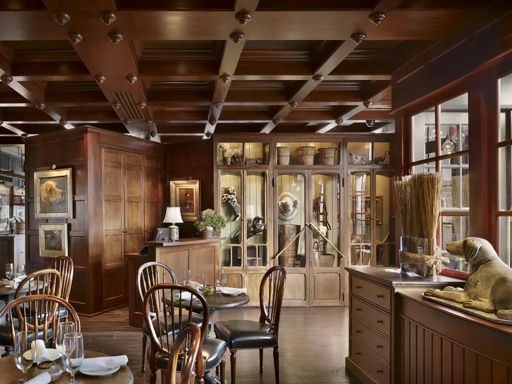 Elegant wooden restaurant interior with coffered ceiling and set tables.