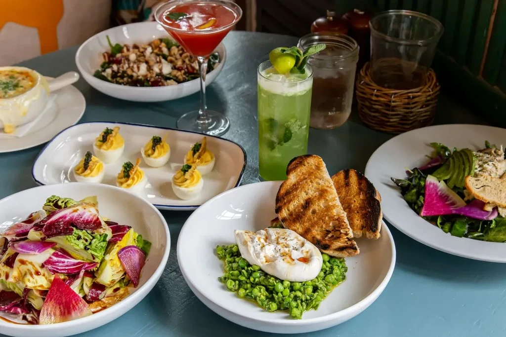 Vibrant table with French onion soup, deviled eggs, salads, and cocktails.