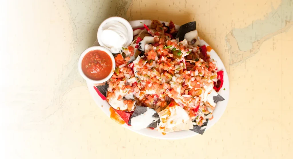 Colorful, fully loaded nachos with cheese, pico, and sauces on a map.