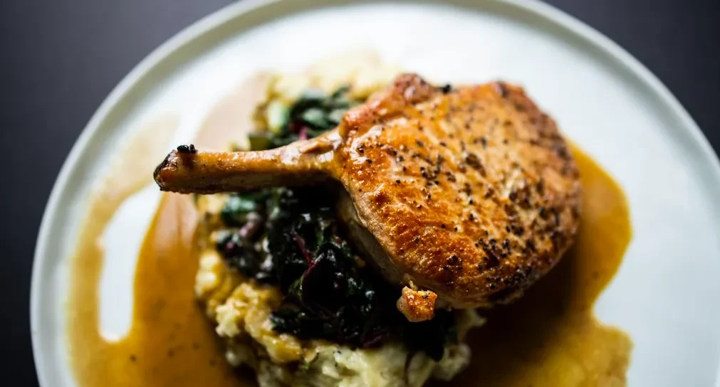 Seared bone-in chop, mashed potatoes, greens, and gravy.