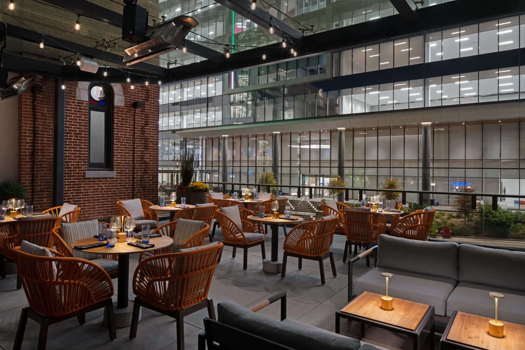 Upscale outdoor dining and lounge area, warmly lit, urban backdrop.