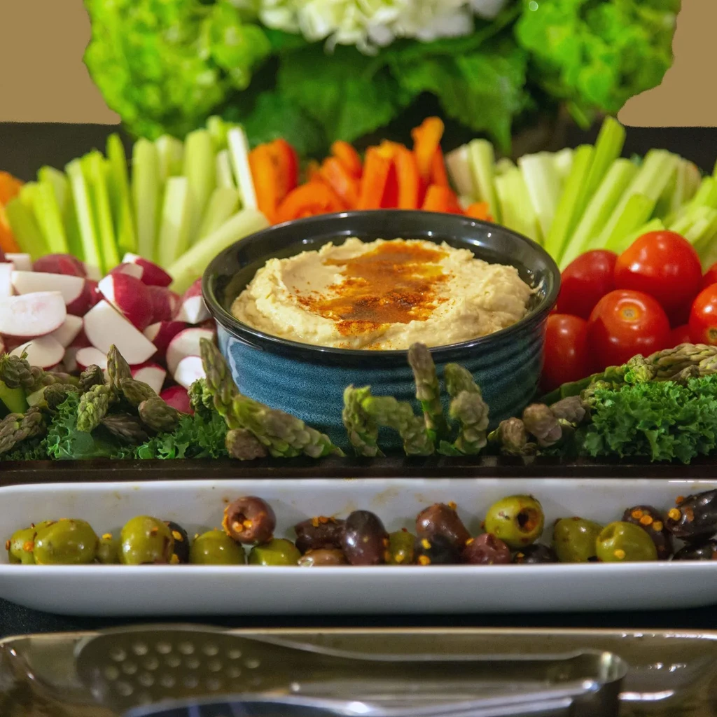 Platter of hummus, radishes, asparagus, celery, peppers, tomatoes, and olives.