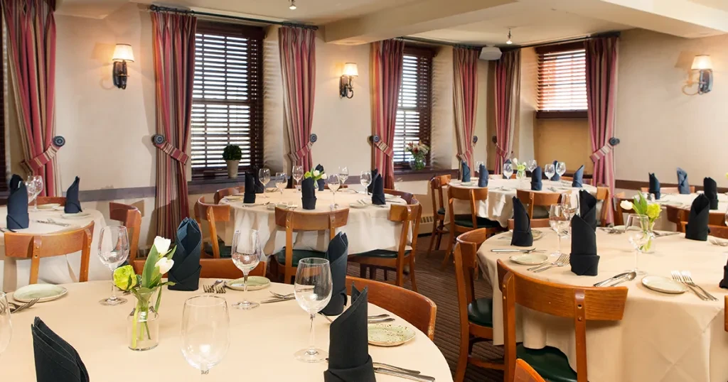 Empty, elegant restaurant dining room with set tables and floral accents.