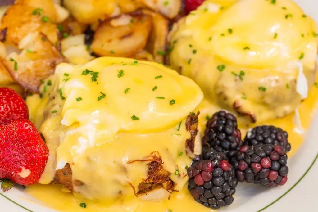 Eggs Benedict with hollandaise, roasted potatoes, fresh strawberries and blackberries.