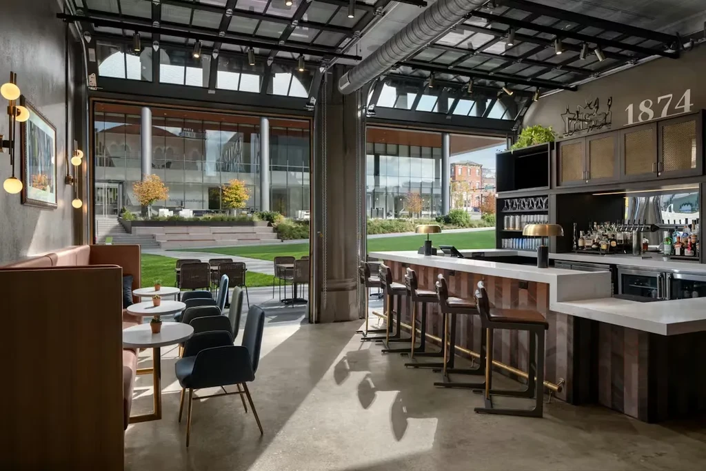 Industrial-chic restaurant interior with lounge, bar, and outdoor view.