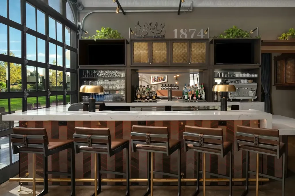 Sophisticated bar interior with white marble counter, brown stools, and elaborate back bar.