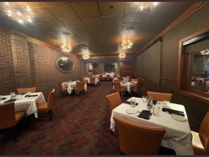 Elegant restaurant dining area with set tables, starburst lights, and brick wall.