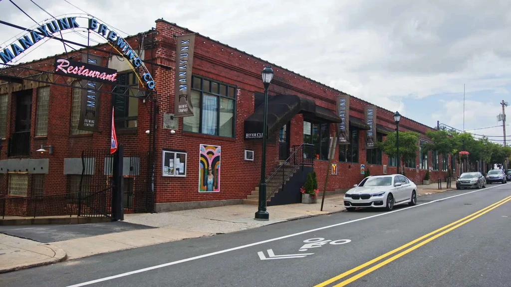 Manayunk Brewing Co. Restaurant, large red brick building with neon signs.