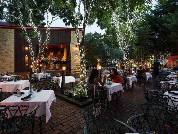 Lively outdoor restaurant patio with glowing string lights and diners.