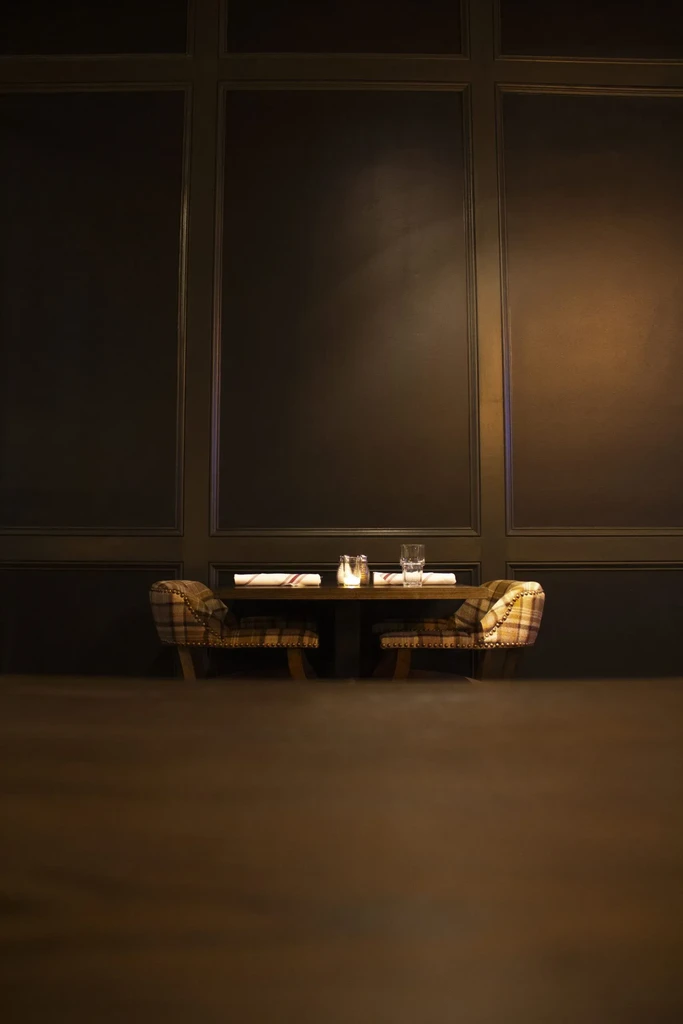 Table for two with plaid chairs and candle glow.