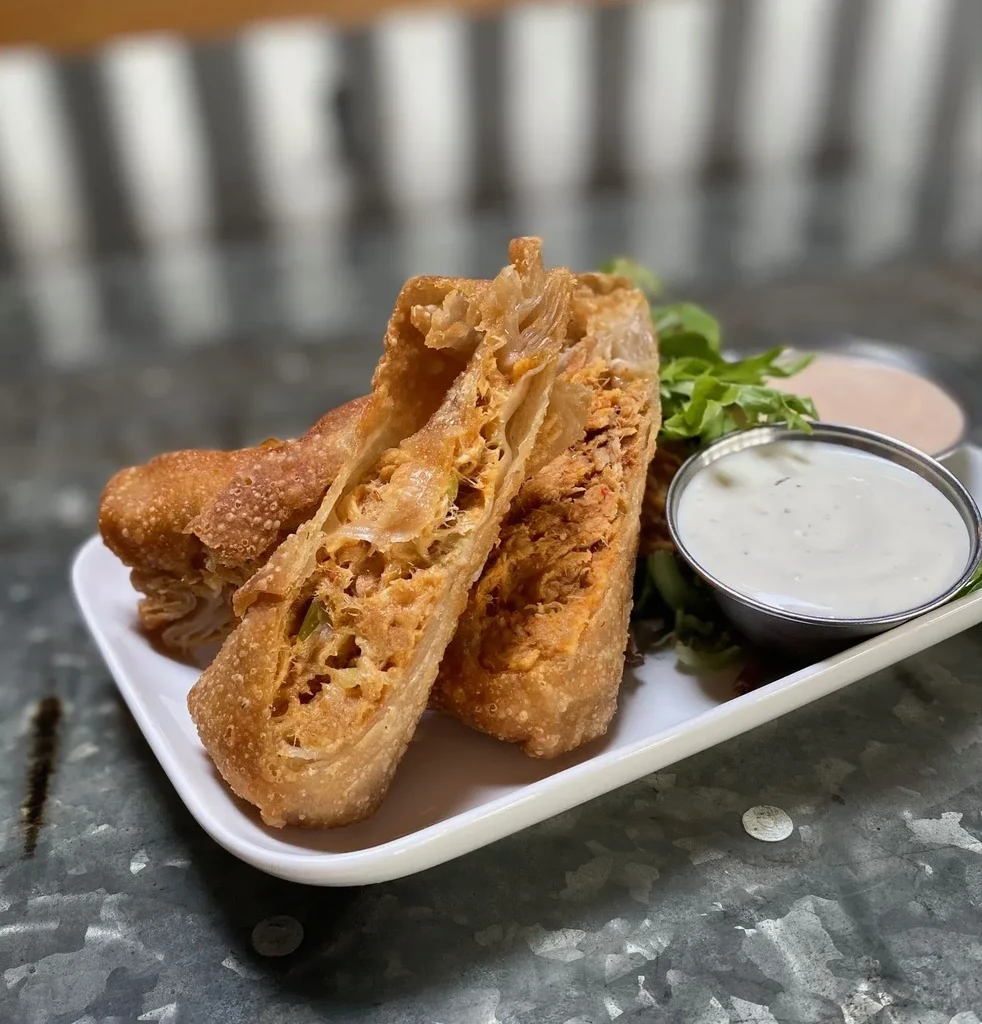 Three crispy fried rolls with savory filling and two dipping sauces.