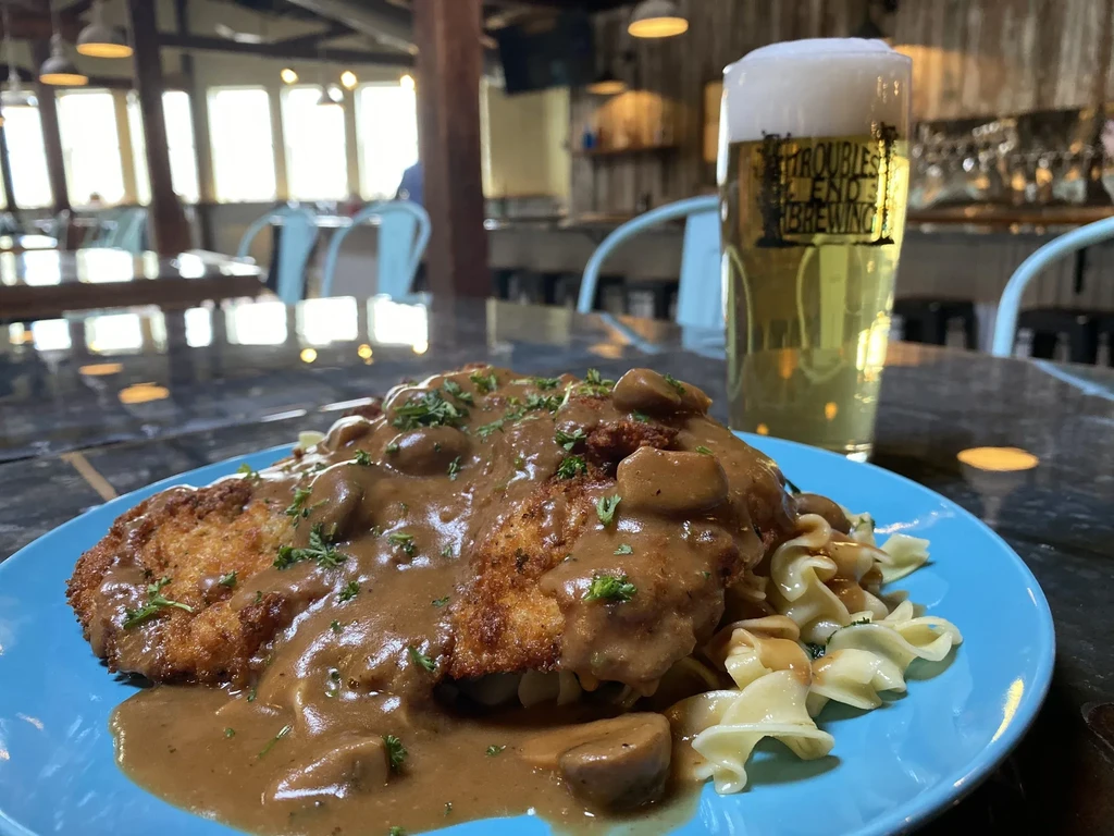 Breaded schnitzel, mushroom gravy, noodles, and Troubles End Brewing beer.