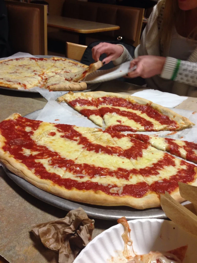 Two large pizzas on a restaurant table, one being served.