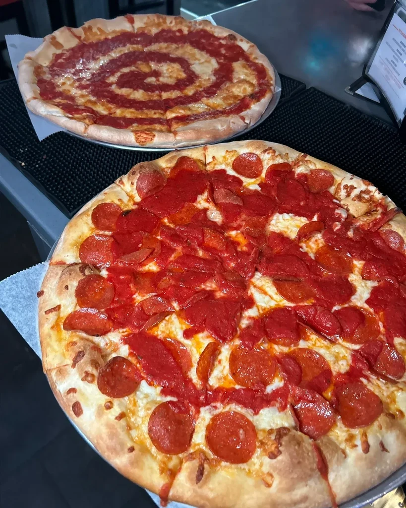 Two restaurant pizzas: one pepperoni, one with spiral tomato sauce.