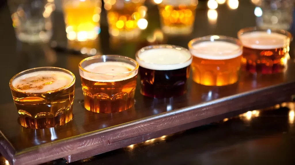 Close-up: Five varying beers in a flight on a wooden paddle.