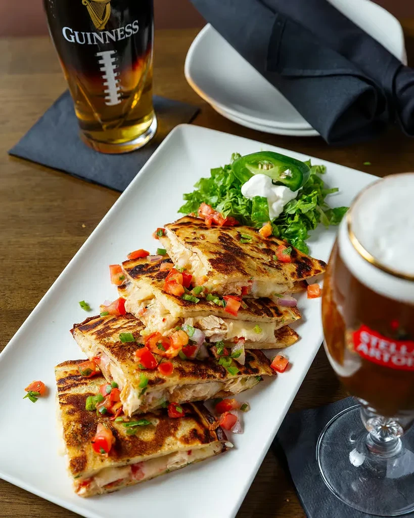 Grilled quesadillas with diced vegetables, sour cream, and two beers.