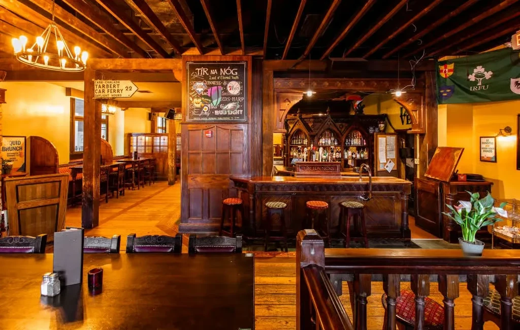 Traditional Irish pub interior, dark wood bar, tables, and chalkboard.