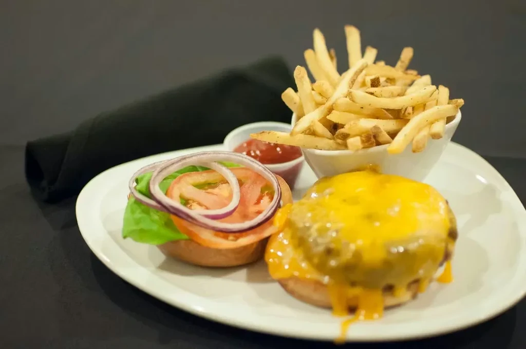 Close-up of a cheeseburger, french fries, and ketchup on a plate.