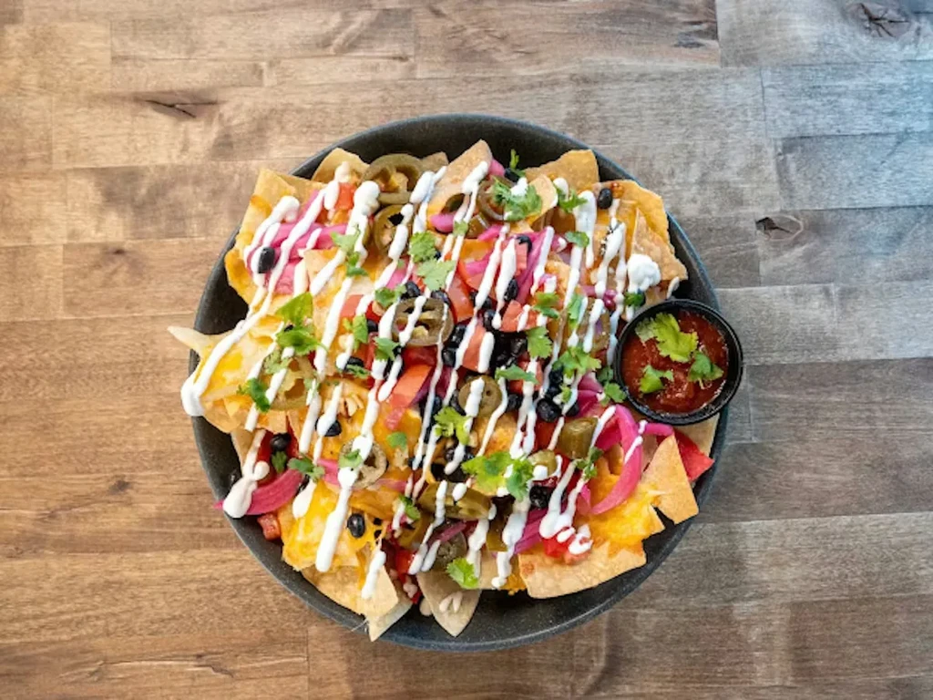 Overhead view of loaded nachos with cheese, beans, vegetables, and salsa.