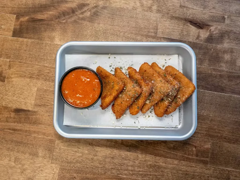 Six fried appetizers with marinara sauce in a silver tray on wood.