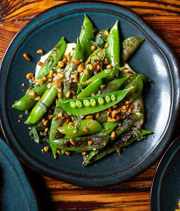 Grilled sugar snap peas, some split, with nuts, herbs, creamy base.