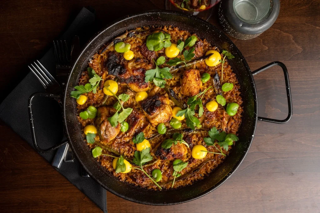 Savory paella with chicken, broad beans, herbs, and caramelized crust.