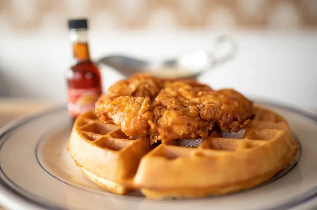 Golden-brown waffle with crispy fried chicken on a blue-rimmed plate.